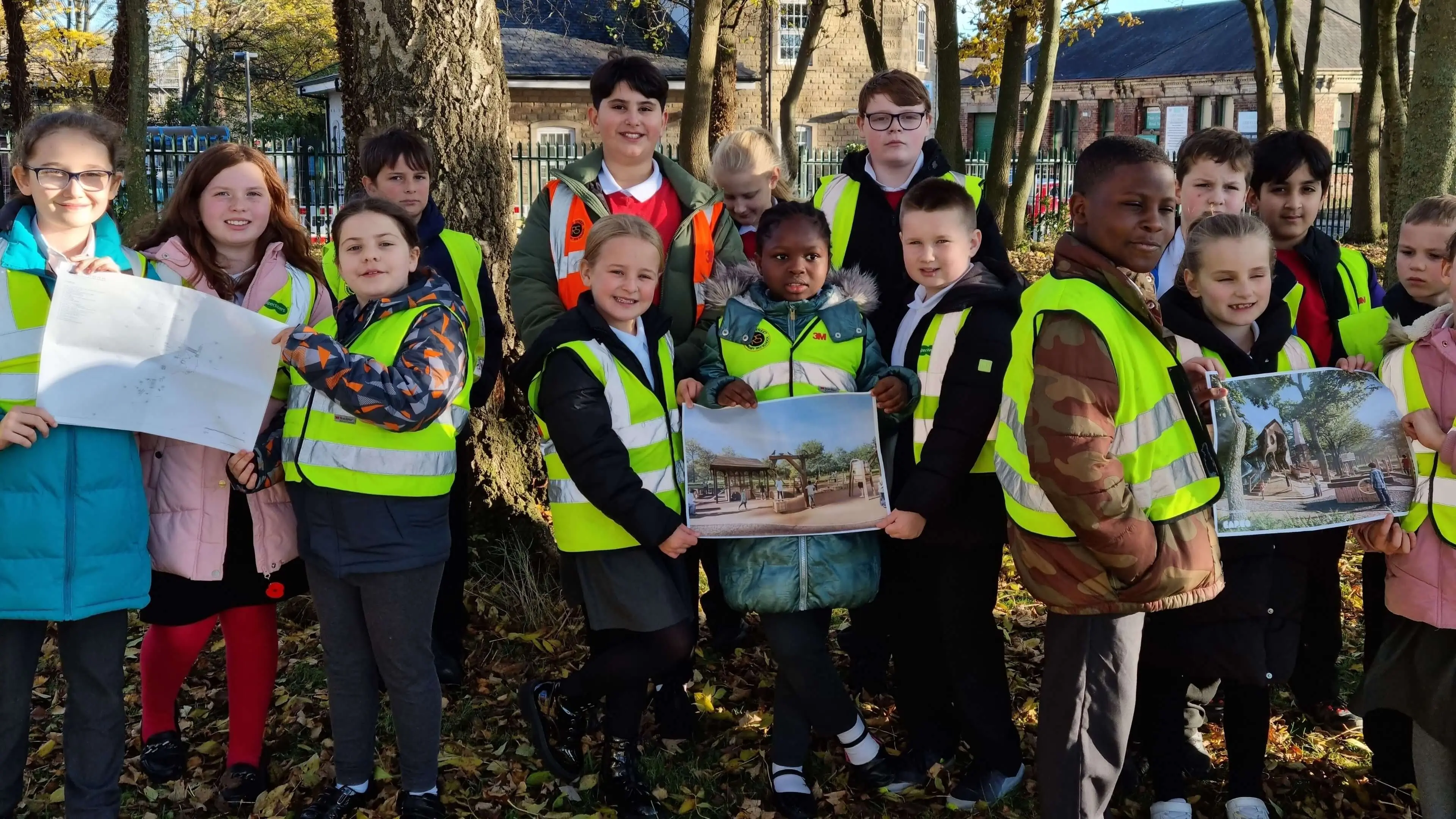 School children in high visibility jackets holding up CGI images of Wagon Woods