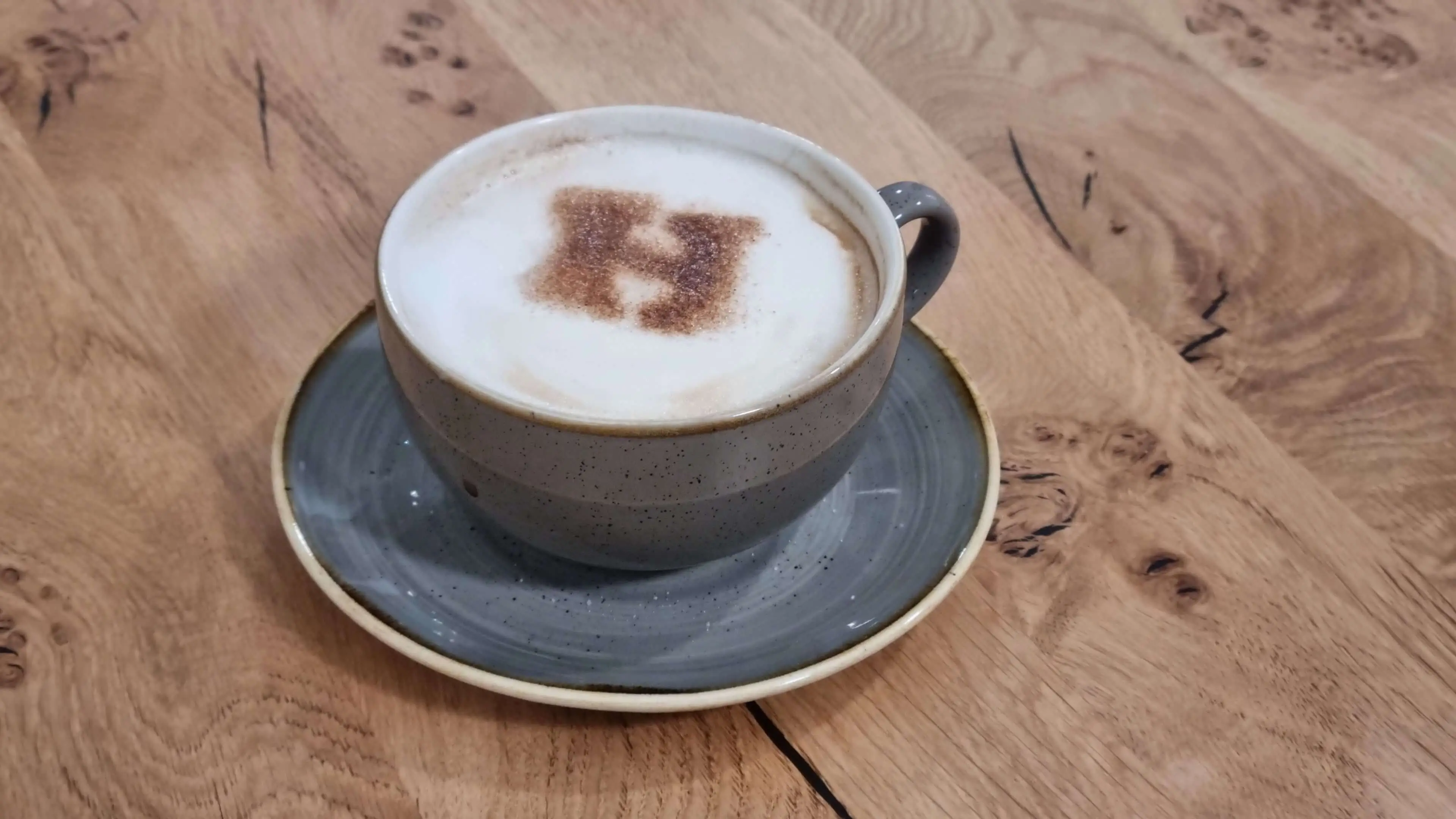 Cup of coffee with a chocolate powder H in the milk foam